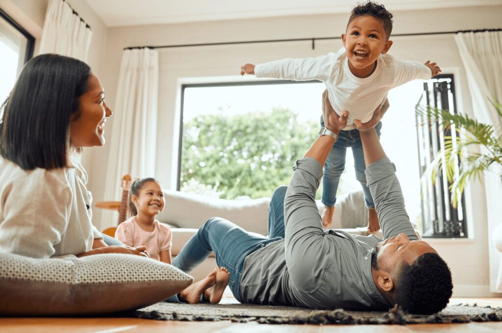 Rhode Island family enjoying a joyful moment on the floor in their pest-free home, made possible by Pro Mosquito Solutions pest control services.