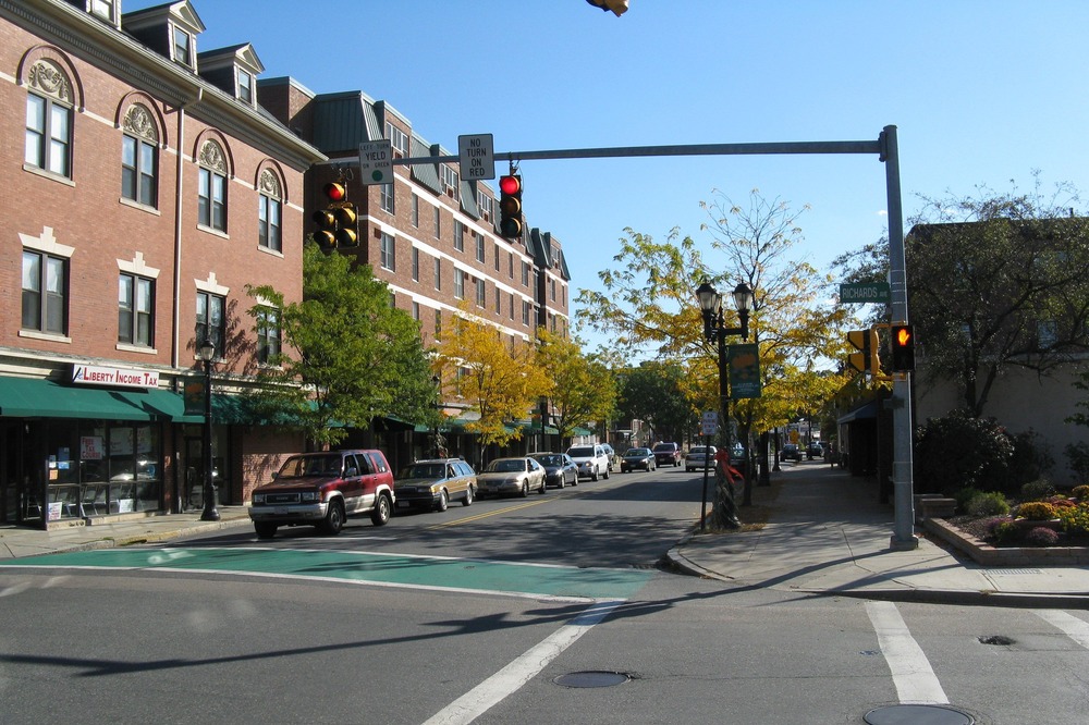 Busy street corner at Richards Avenue and North Washington Street in Downtown North Attleborough, showcasing historic buildings, local shops, and a lively atmosphere.