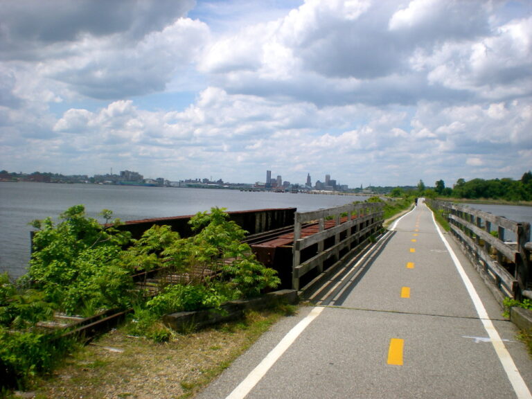 Scenic view of the East Bay Bike Path in East Providence, RI, running alongside the Providence River with lush greenery and waterfront views.