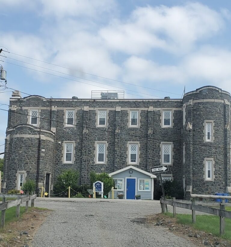 Tranquil view of the historic Cumberland Monastery in Cumberland, RI, with lush greenery and walking trails under a clear sky.