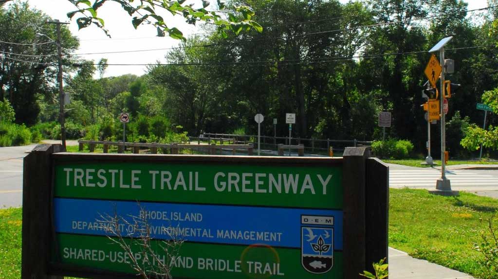 Trestle Trail Greenway in Coventry, RI, a long, straight trail surrounded by lush trees, ideal for walking, biking, and outdoor activities.